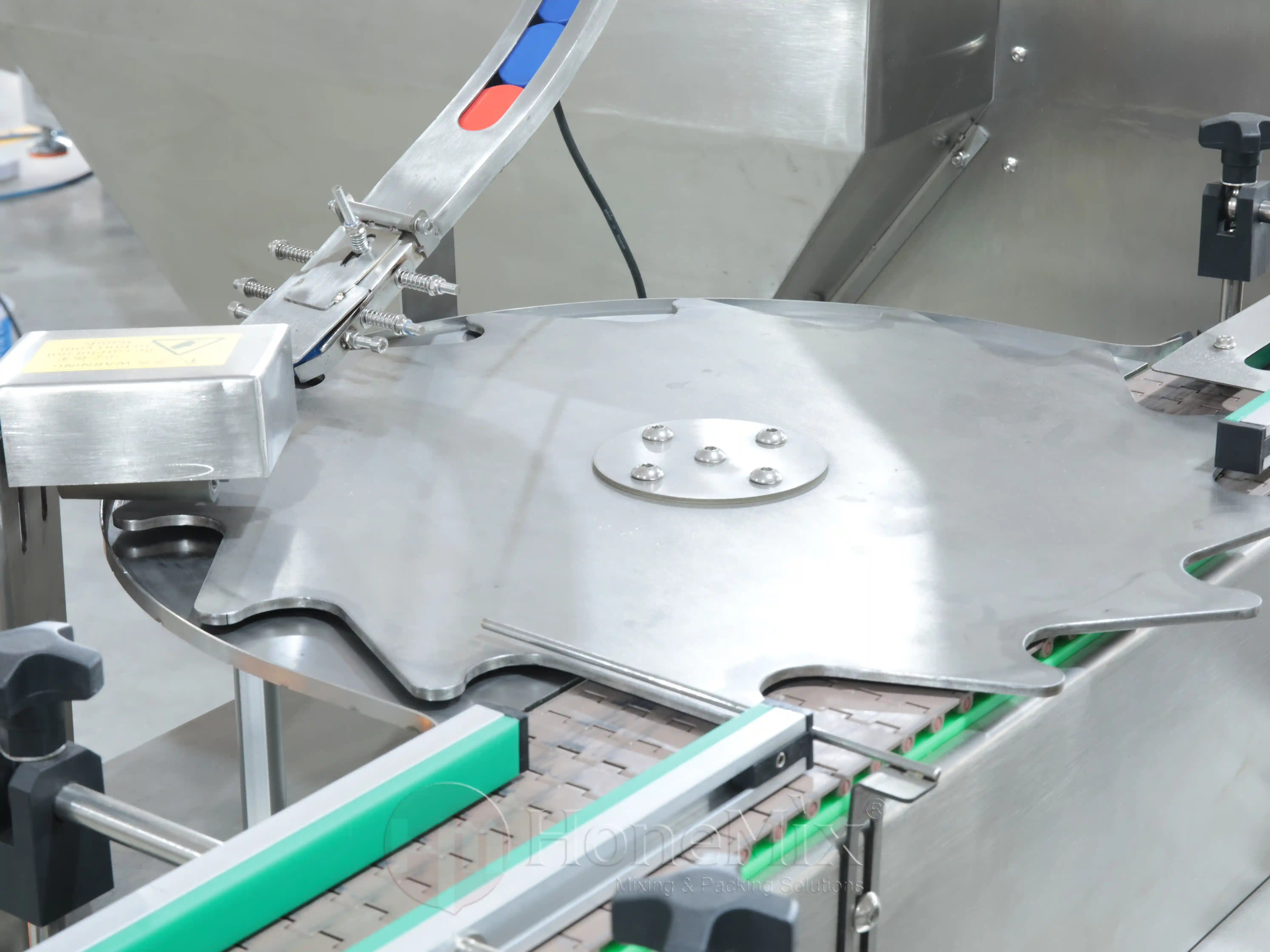 Close-up of the cap placement and pressing station on an automatic jar capping line