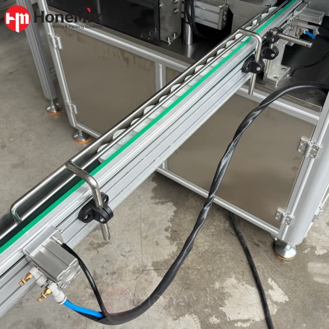 Adjustable infeed conveyor transferring empty jars to the automatic filling machine